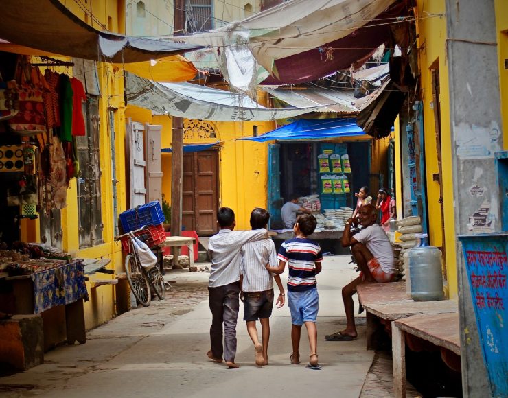 three boys walking between buildings at daytime